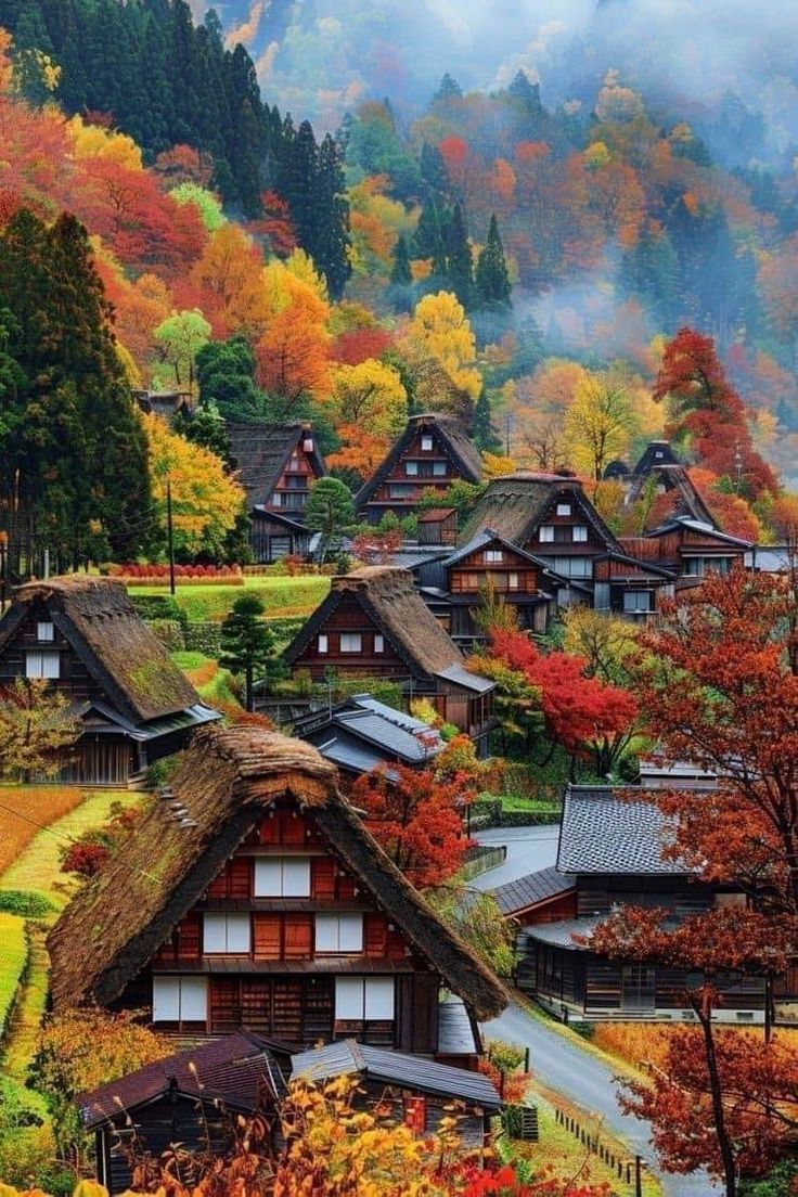 an autumn scene with houses and trees in the foreground, surrounded by foggy mountains