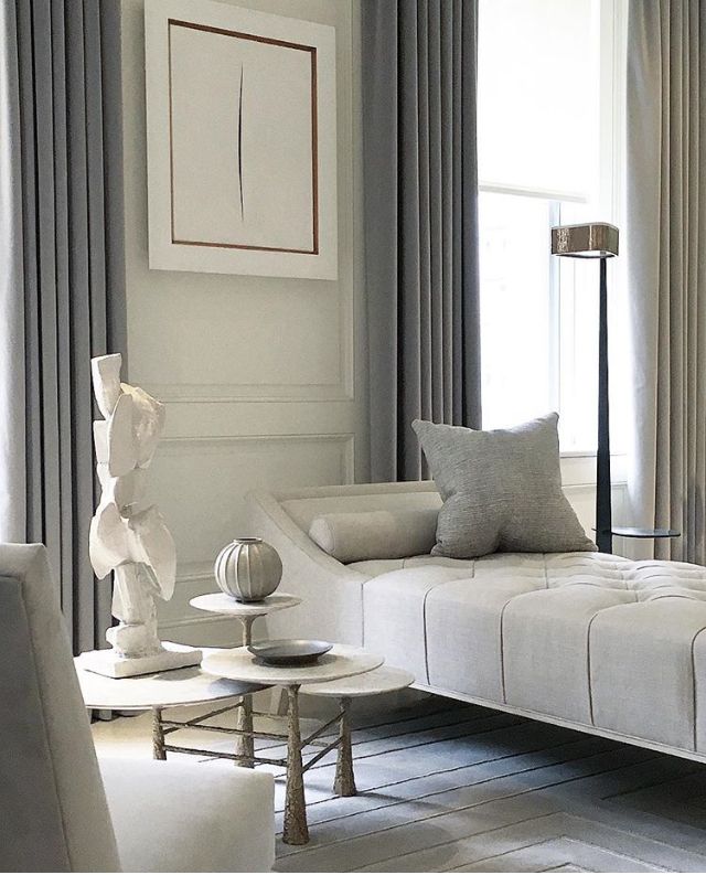 a living room filled with white furniture and gray drapes on the window sill