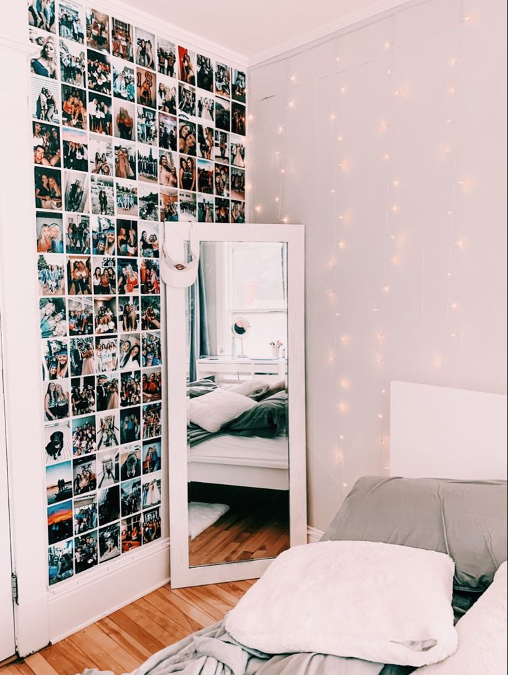 a bedroom with a bed, mirror and lights on the wall above it is decorated with photos