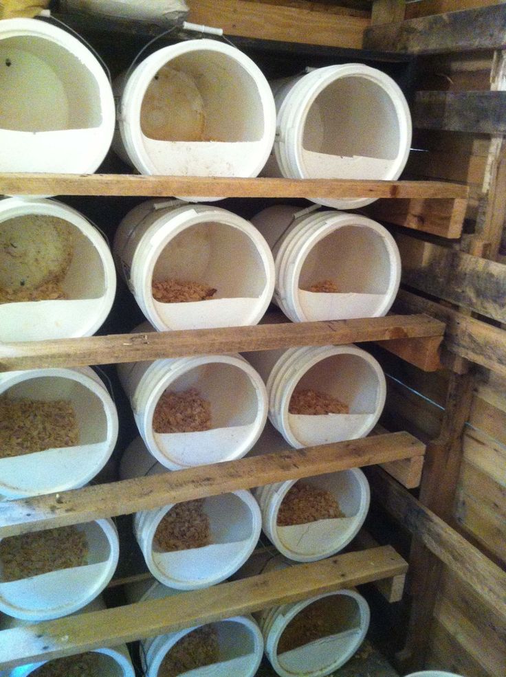 several white buckets are stacked on wooden shelves