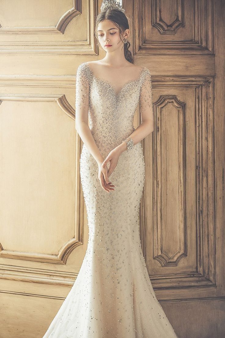 a woman in a wedding dress standing next to a wooden paneled wall and wearing a tiara