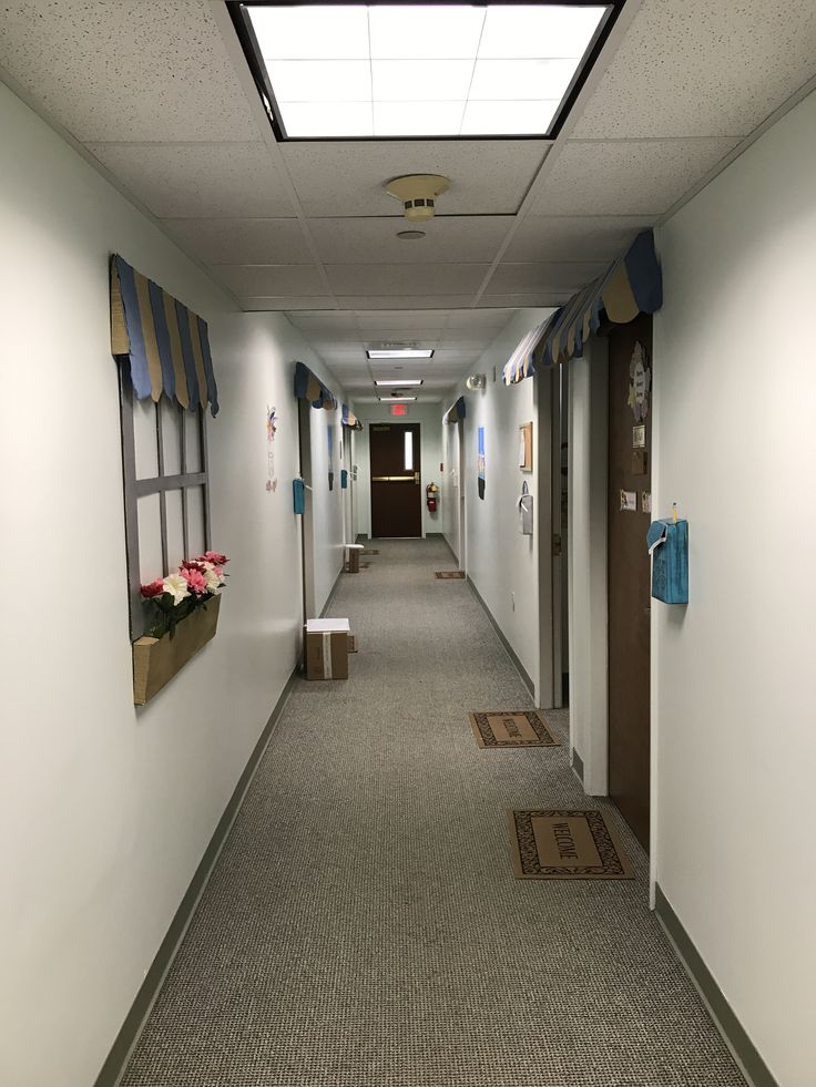 an empty long hallway with no one in it and flowers on the wall next to the doors