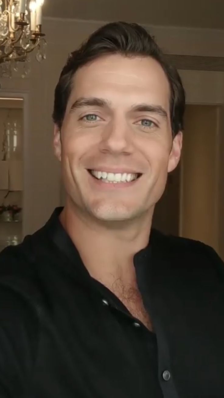 a man smiling in front of a chandelier