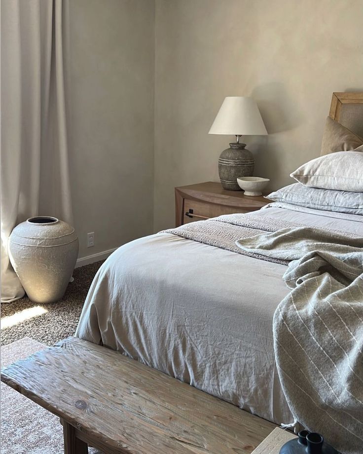 a bed sitting next to a wooden bench in a bedroom on top of a carpeted floor