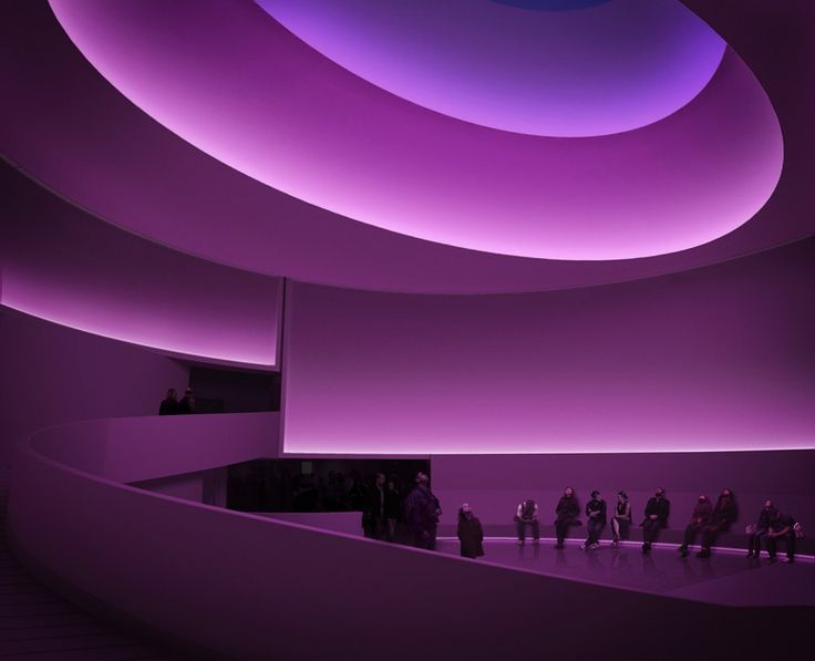 people are standing in the middle of a large room with purple lighting on the ceiling