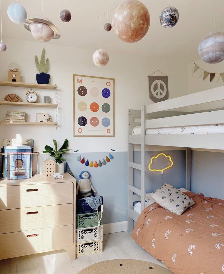 a child's bedroom with bunk beds and planets hanging from the ceiling above them