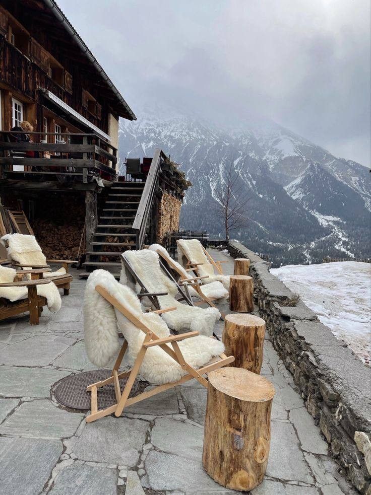 two lounge chairs sitting on top of a stone patio next to a wooden log table