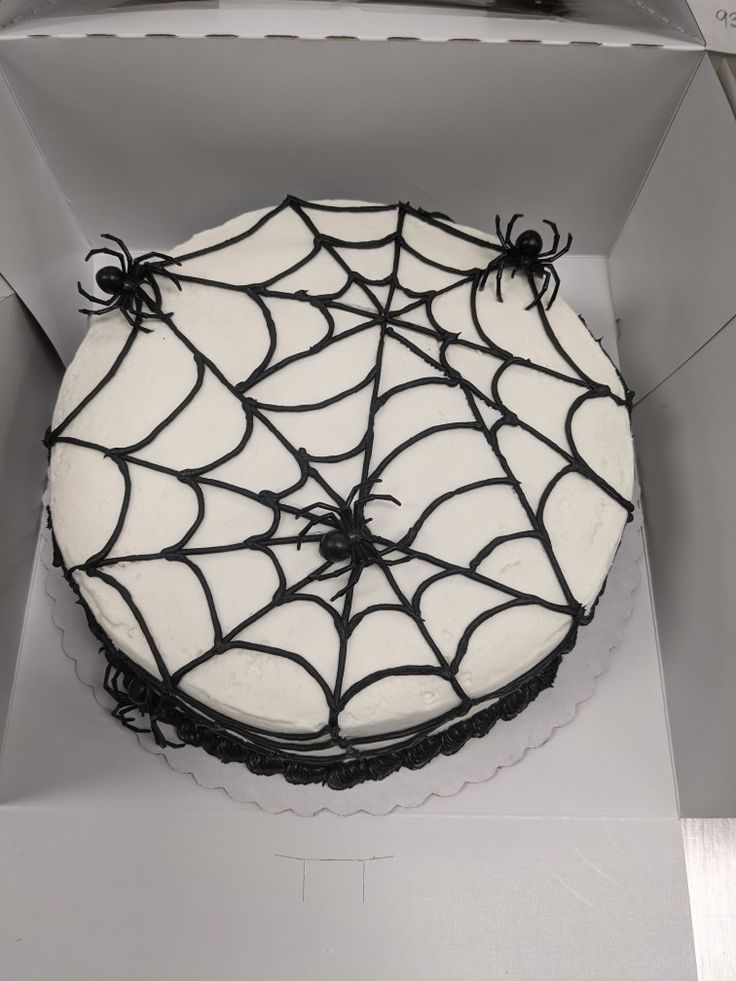 a spider web cake in a box with white frosting and black icing on it