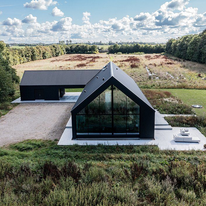 an aerial view of a house in the middle of a field with grass and trees