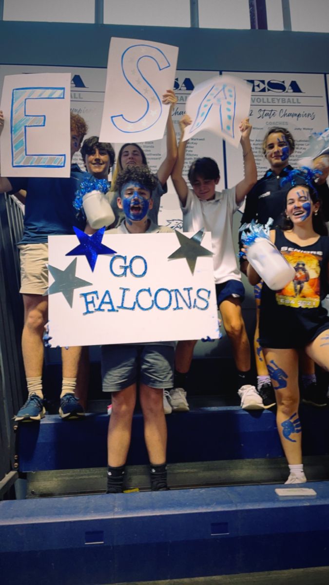 some people are holding up signs and posing for a photo on the bleachers