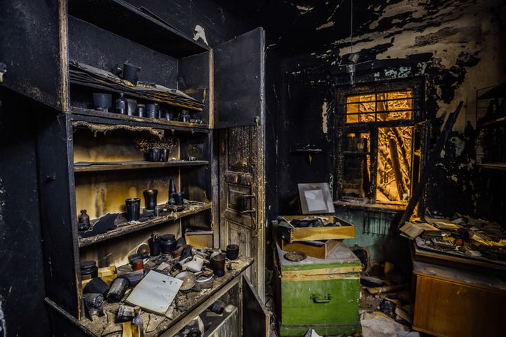 an old run down kitchen with lots of clutter on the floor and shelves in it