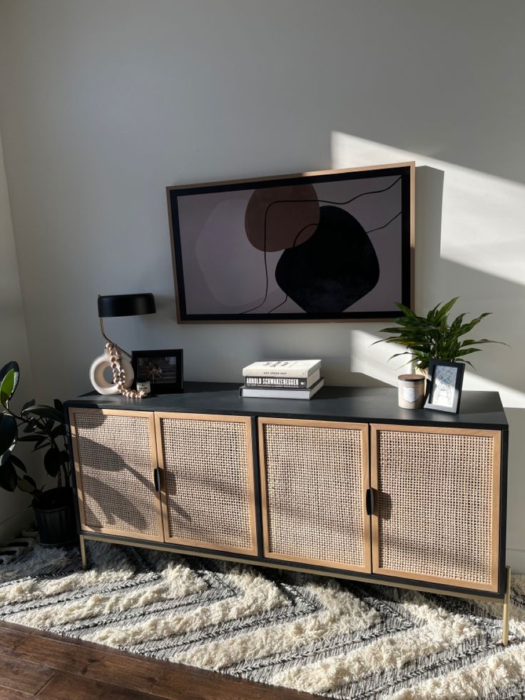 a living room area with a rug, plant and pictures on the wall above it