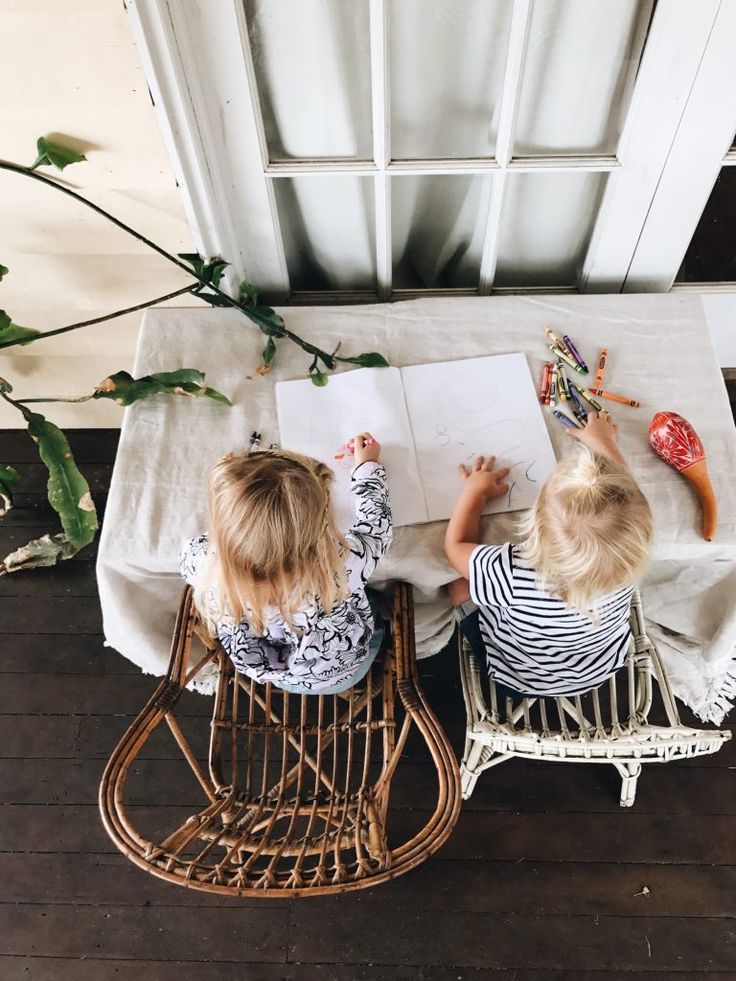 two young children sitting at a table with an open book