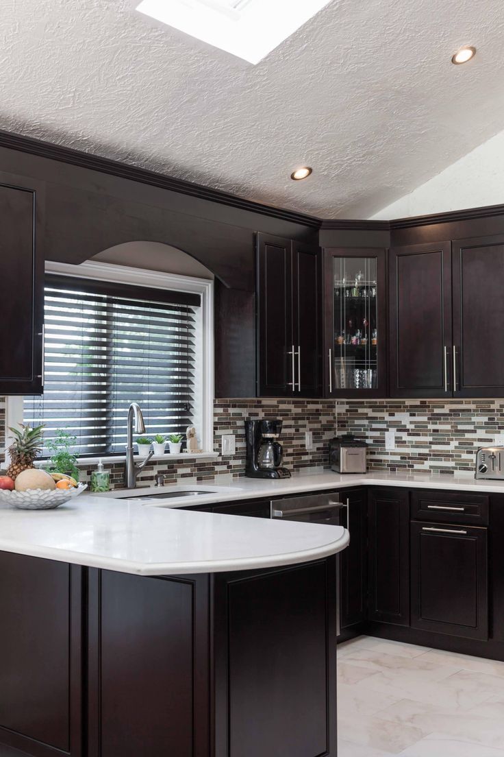 a kitchen with dark wood cabinets and white counter tops, along with a center island