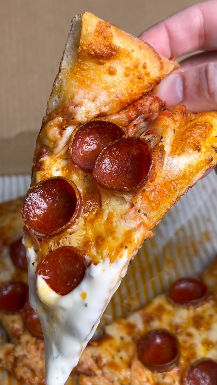 a slice of pepperoni pizza being held up