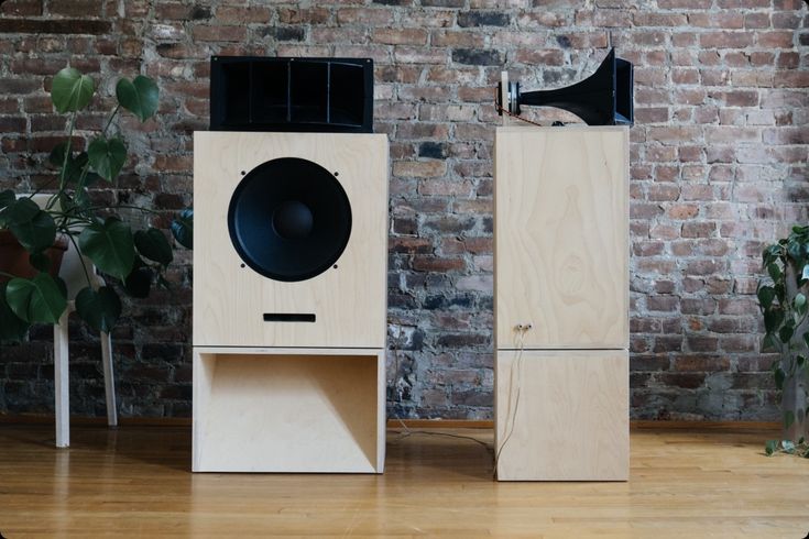 two speakers sitting next to each other on top of a hard wood floor near a brick wall