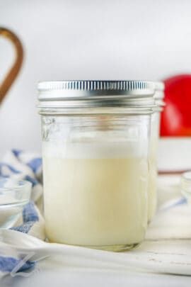 a glass jar filled with liquid sitting on top of a blue and white checkered cloth