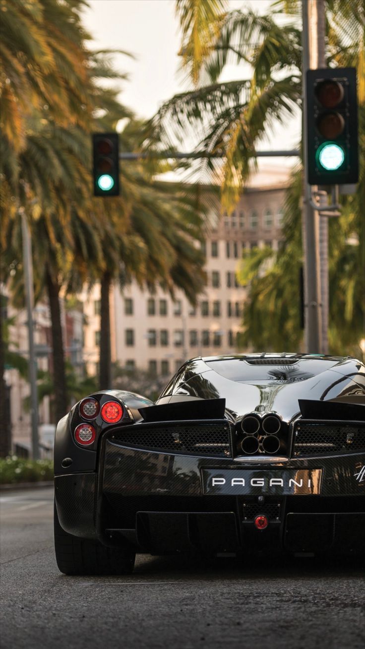 a black sports car is stopped at a green light in the middle of the street