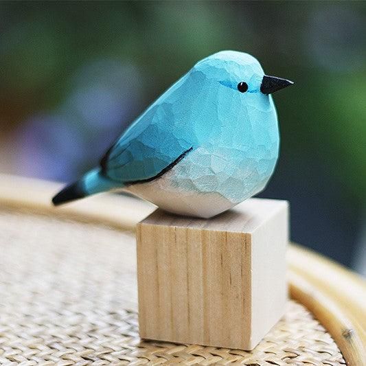 a blue bird sitting on top of a wooden block