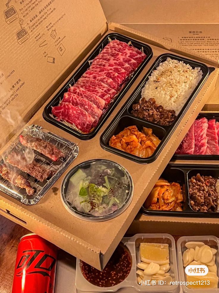 an open box filled with assorted meats and other foods on top of a wooden table