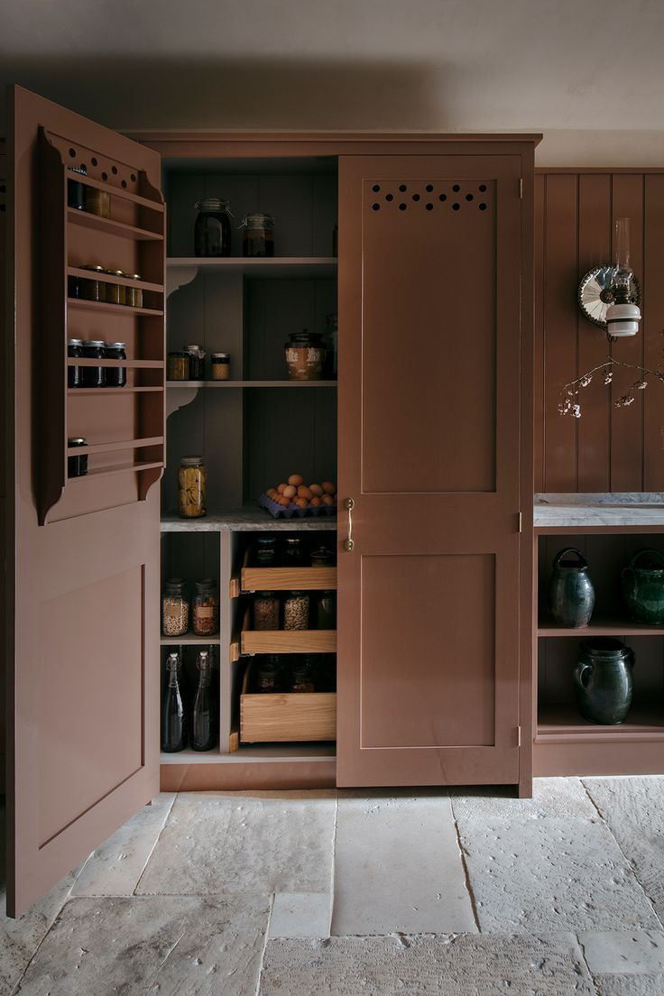 an open cabinet in the middle of a room with shelves and pots on top of it