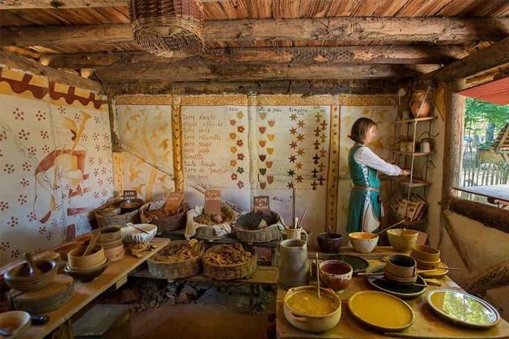 a woman standing in a room filled with lots of bowls and plates on top of wooden tables