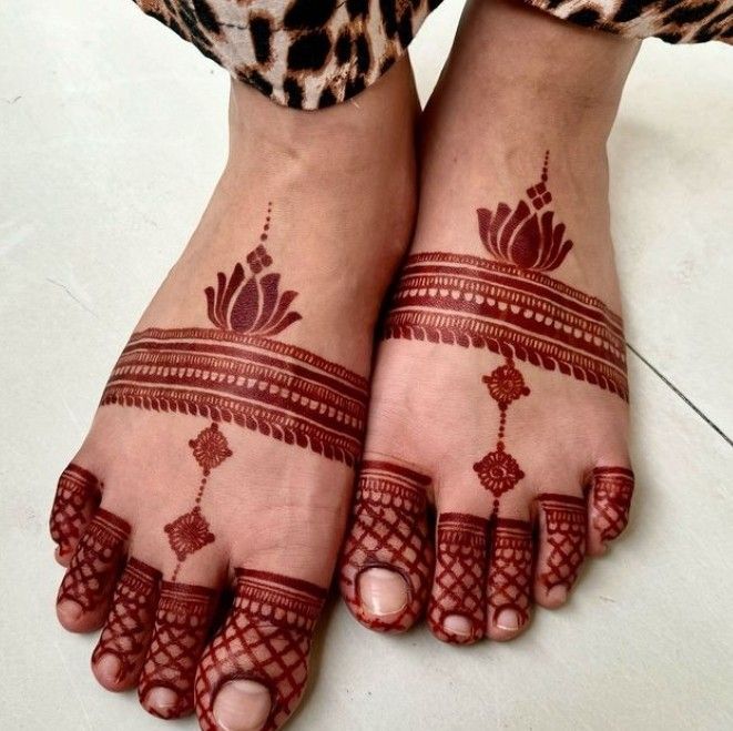 two feet with henna tattoos on them, one is red and the other is white