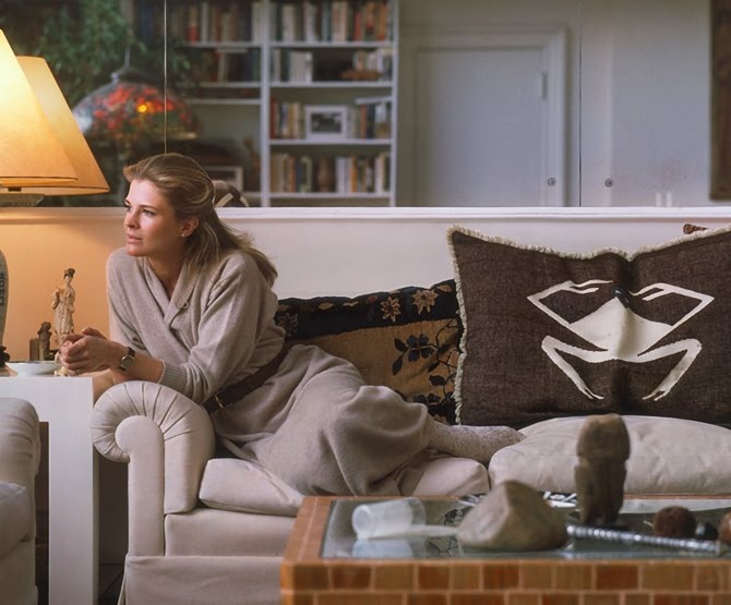 a woman sitting on top of a couch in a living room next to a lamp