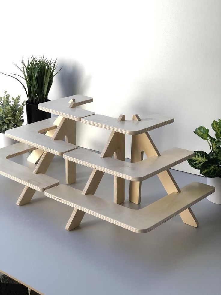 three wooden benches sitting on top of a white table next to a potted plant