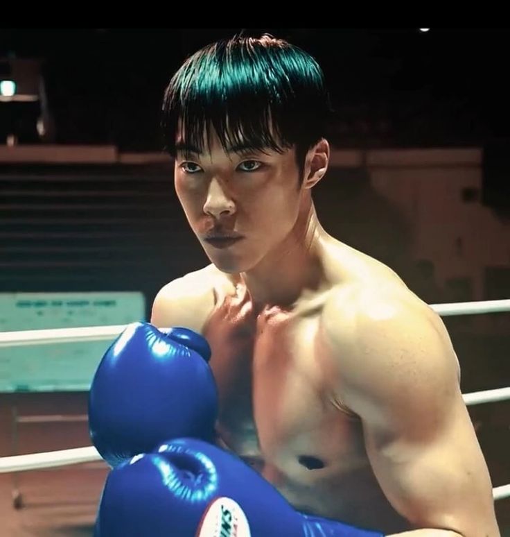 a young man with green hair and blue boxing gloves posing for a photo in the ring