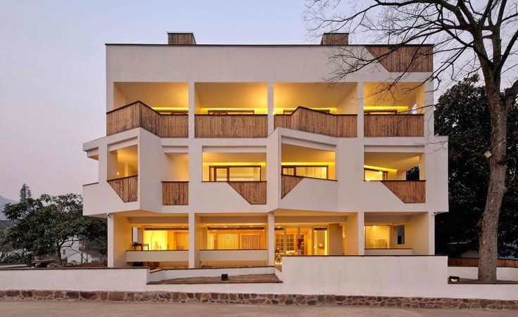 an apartment building with balconies lit up in the windows at dusk, near a parking lot