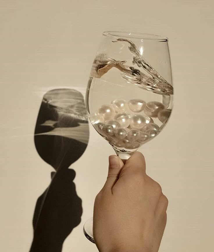 a person holding a wine glass with pearls in it