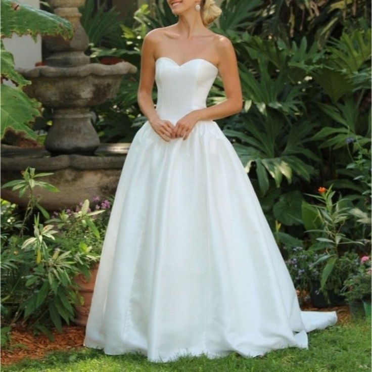 a woman in a white wedding dress posing for the camera with her hands on her hips