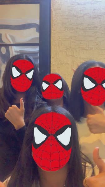 three girls wearing spider - man masks in front of a mirror with their fingers up