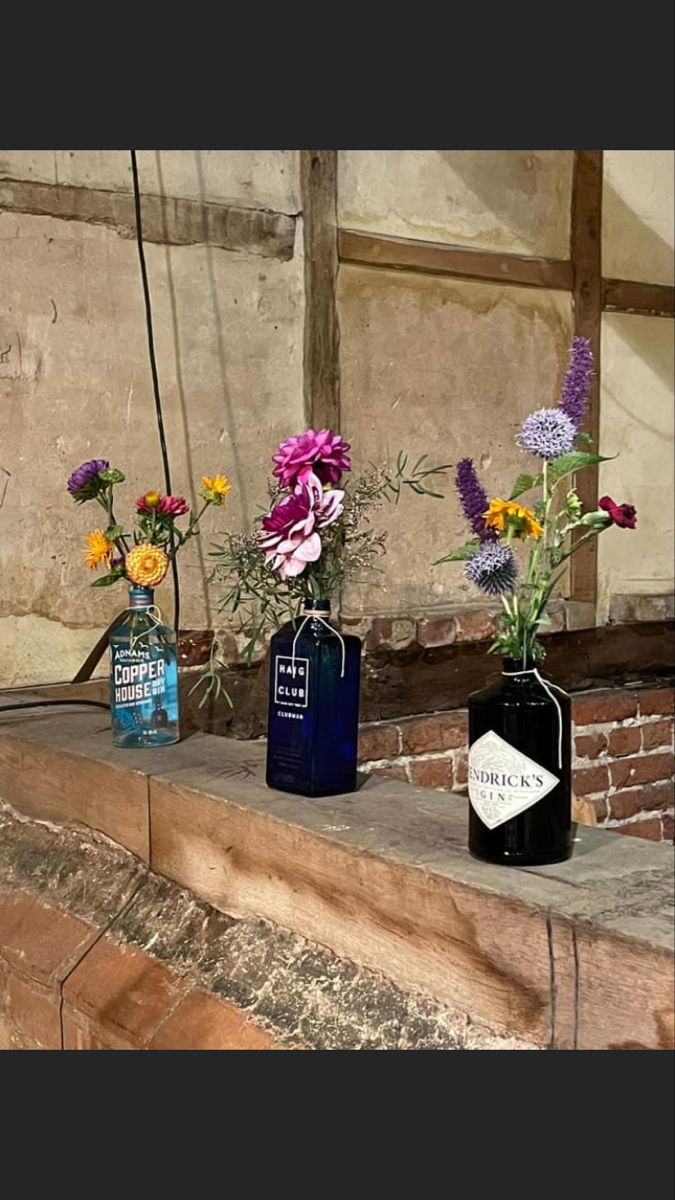 three vases with flowers are sitting on a ledge in front of a brick wall