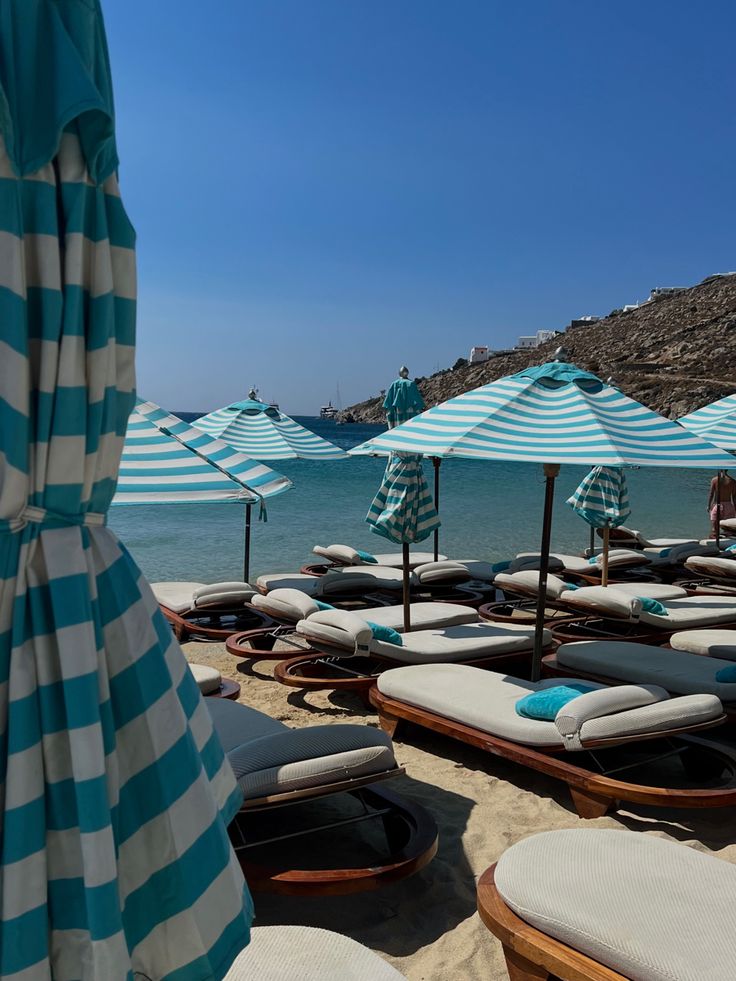 lounge chairs and umbrellas are lined up on the beach