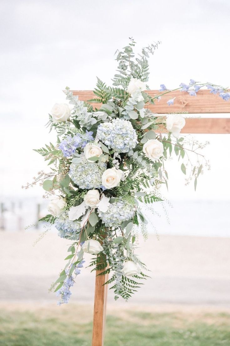 a wedding arch with flowers and greenery on the beach front area for an outdoor ceremony