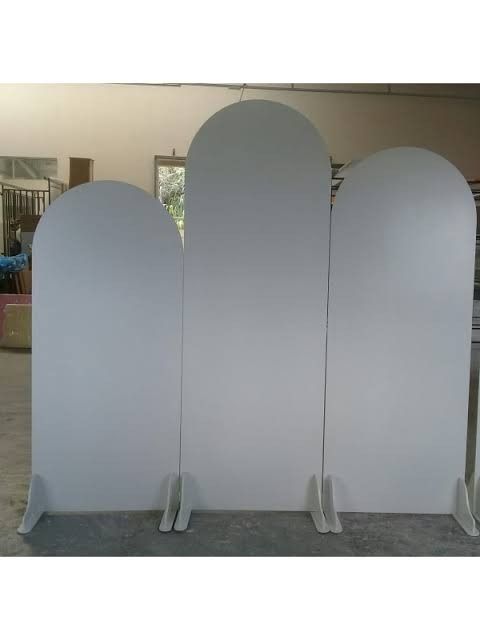 three white arches are standing next to each other in the middle of an empty room