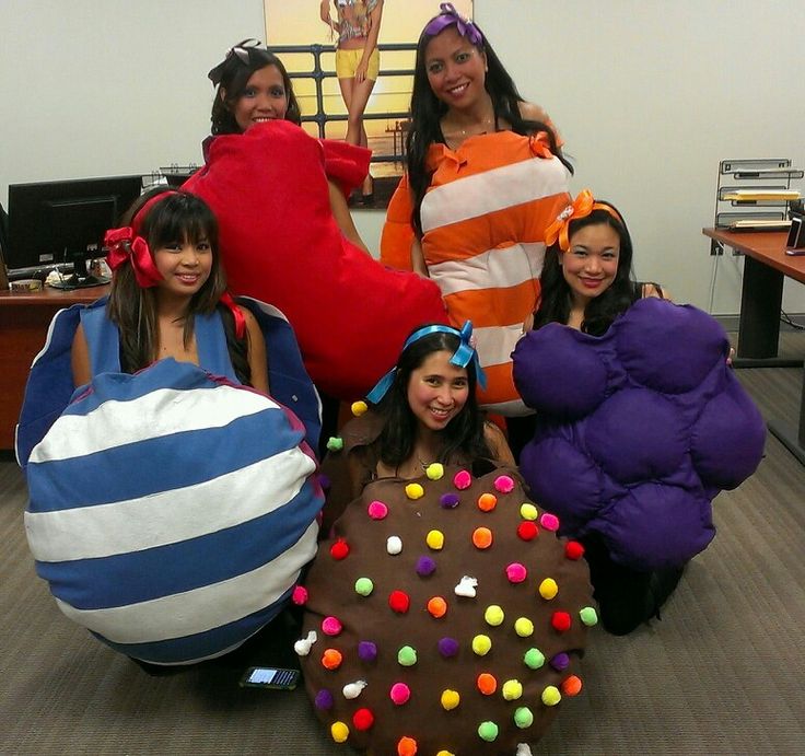 four girls dressed up in costumes posing for the camera with giant pillows and balls around them