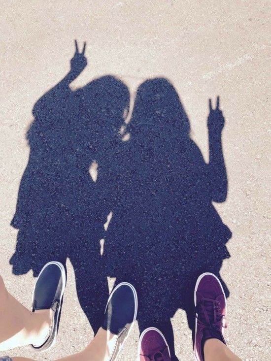 two people standing next to each other with their hands in the air and shadows on the ground