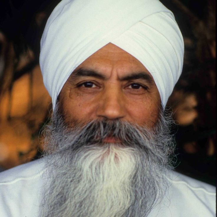 a man with a long beard wearing a white turban and looking at the camera