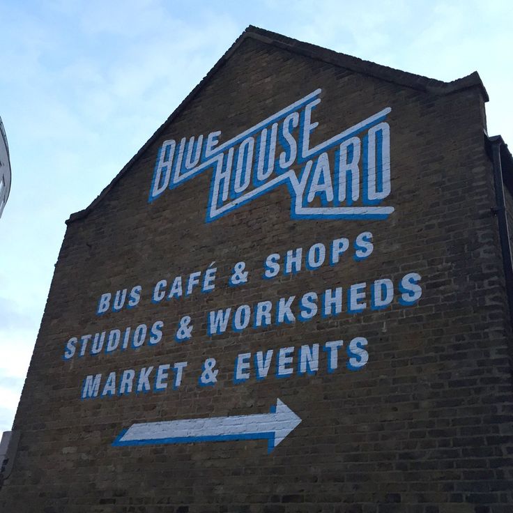 a sign on the side of a building that says blue house yard bus cafe and shops