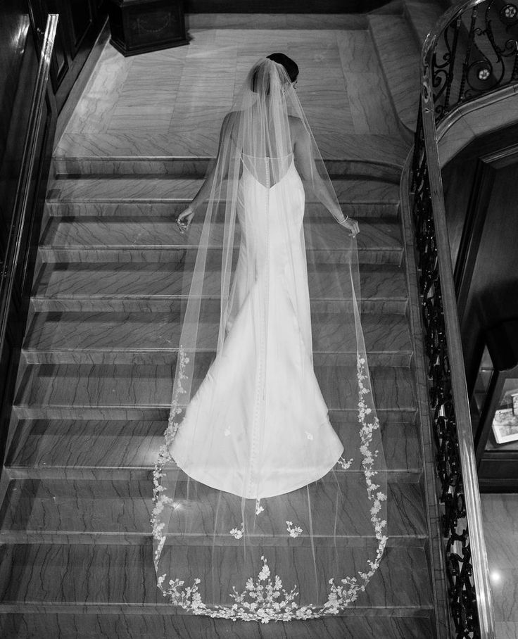 the bride is walking down the stairs in her wedding dress