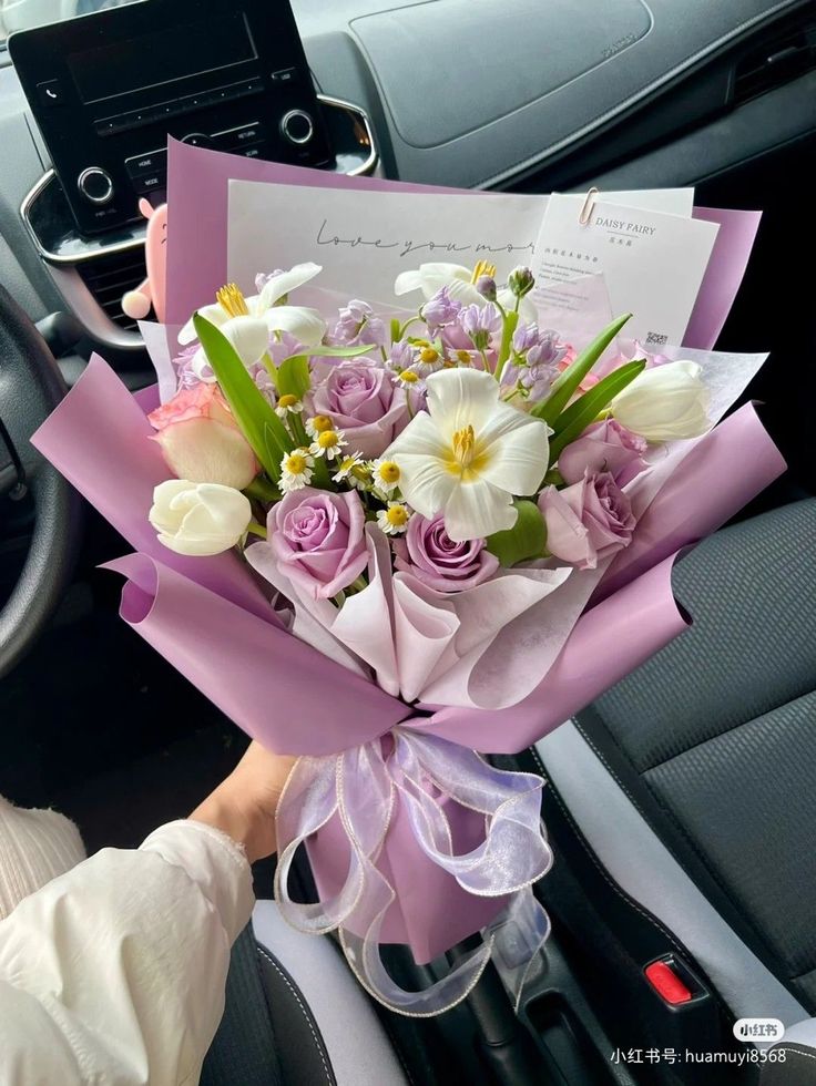 a bouquet of flowers is being held by a woman in the driver's seat