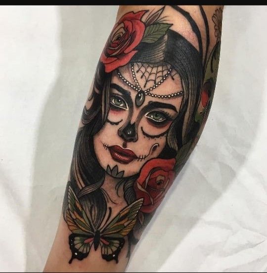 a woman's face with roses and a butterfly on her left arm, done in black and grey