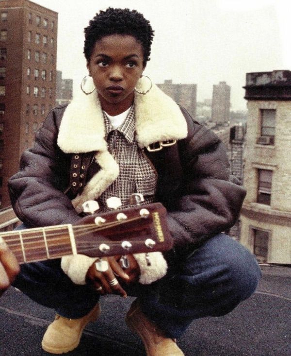 a young man sitting on top of a roof holding an acoustic guitar in his hands