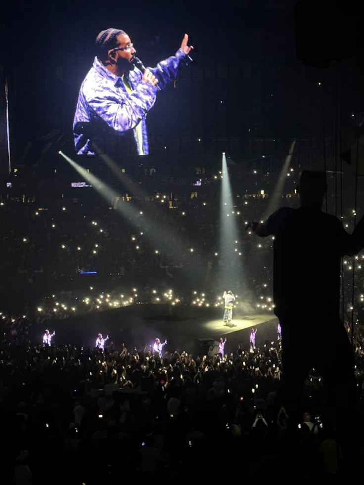 a man standing on top of a stage in front of a crowd at a concert