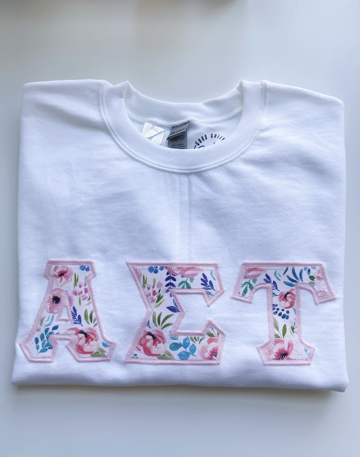 a white t - shirt with the letters fraternity and flowers painted on it's chest