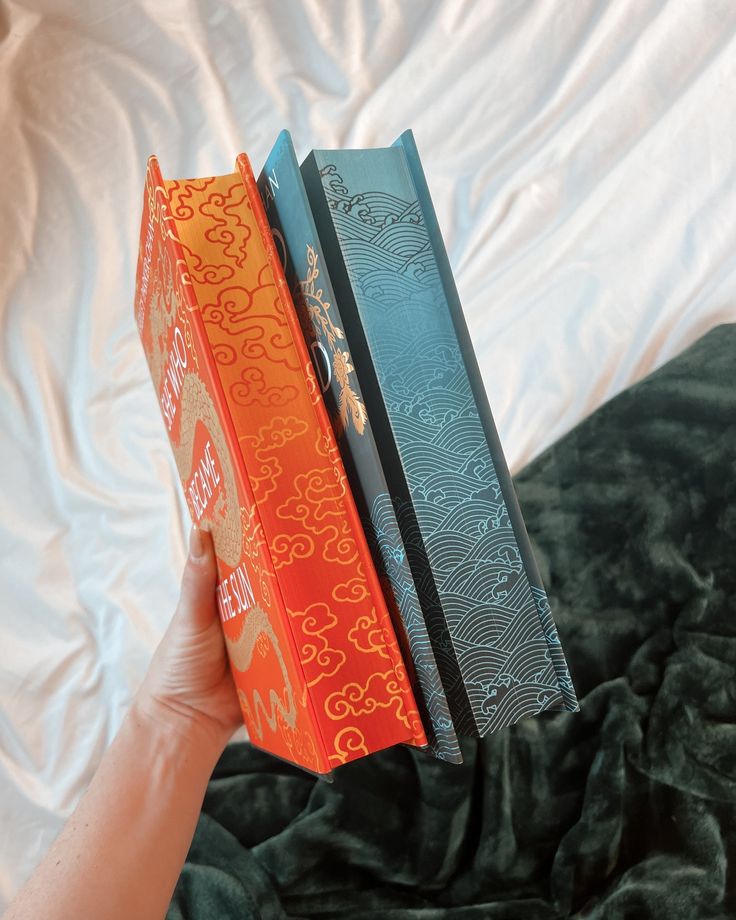 two books sitting on top of each other in front of a white sheet covered bed