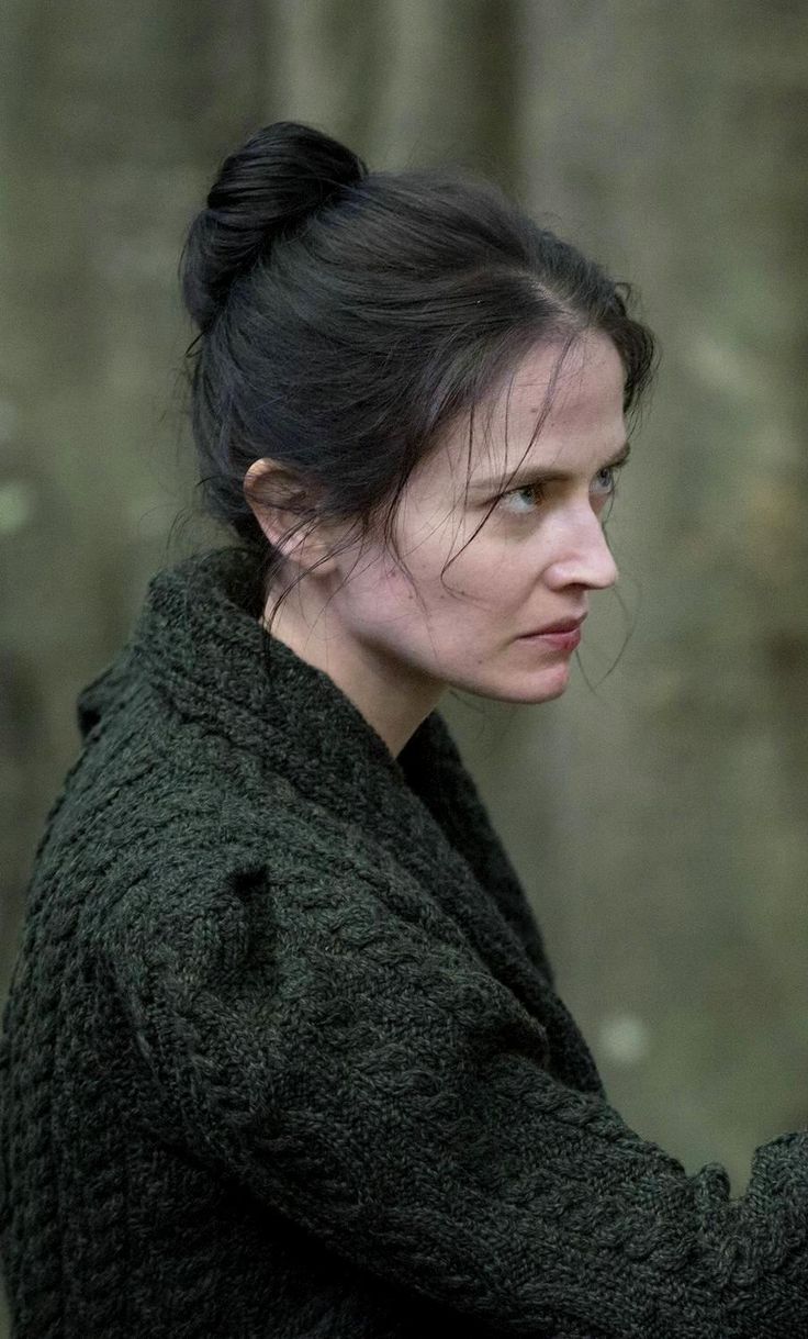 a woman holding a cell phone up to her ear in front of a forest background